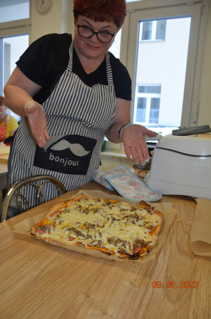 Pani Marzena z terapii pochyla się nad upieczoną pizzą