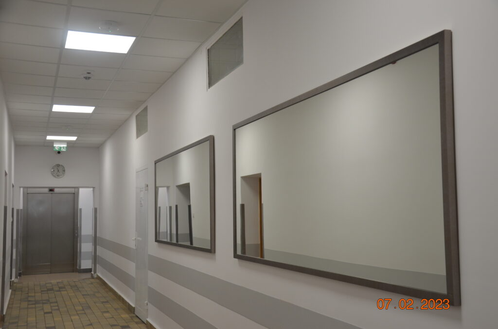 długi , jasny korytarz w budynku głównym. na ścianach prezentują się dwa duże  lustra