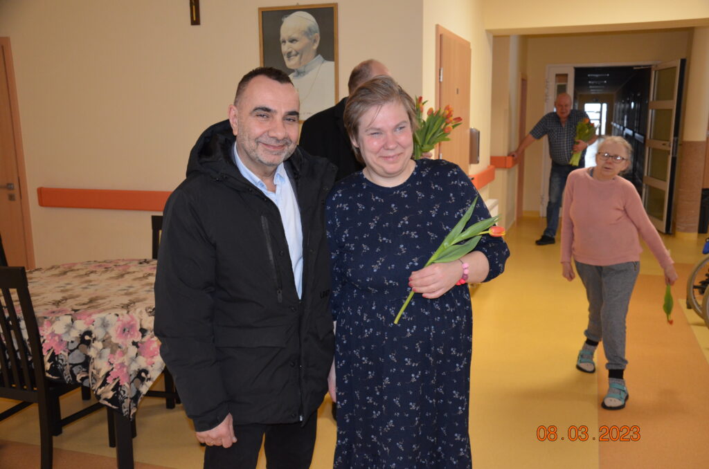 Pan dyrektor wręcza kwiaty pani beacie. Uśmiechają się.
