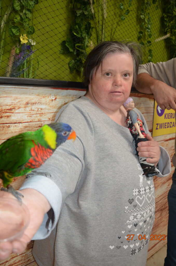 Pani Alicja pozuje do zdjęcia  trzymając w ręku papugę 