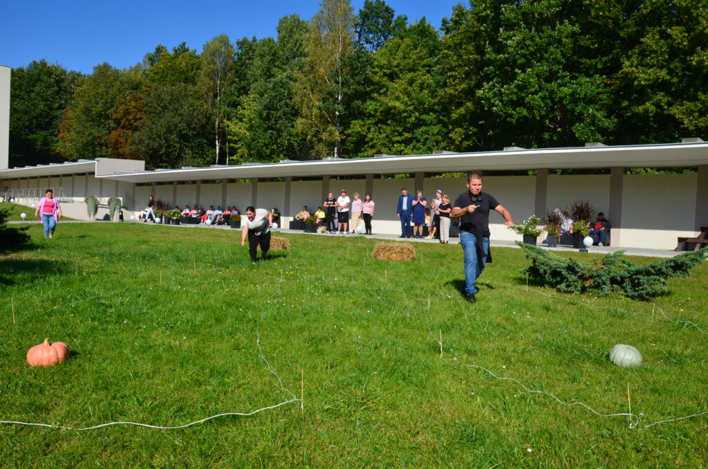 Słoneczny dzień, na trawie zawody sportowe. młody mężczyzna ubrany w czarną koszulkę rywalizuje z dziewczyną niosąc na łyżeczce jajko