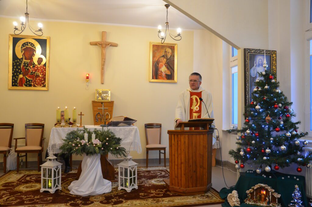 w kaplicy. ołtarz główny. przy ambonie ksiądz Andrzej Sowiński przemawia do mieszkańców. w tle dekoracje świąteczne, choinka