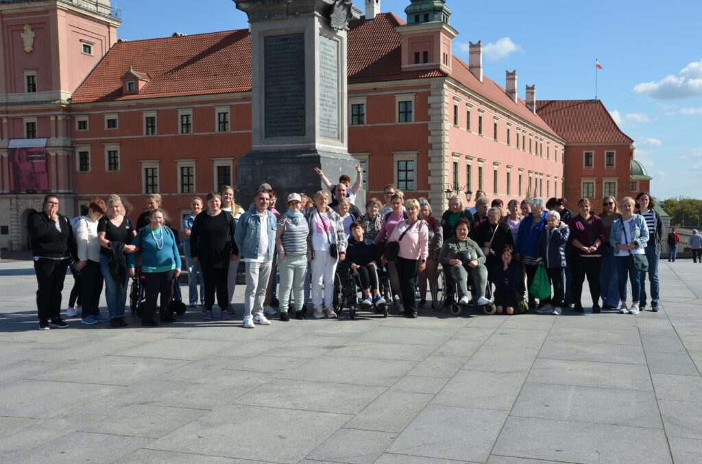 grypa ludzi stoi przy pomniku zygmunta przed zamkiem królewskim w warszawie