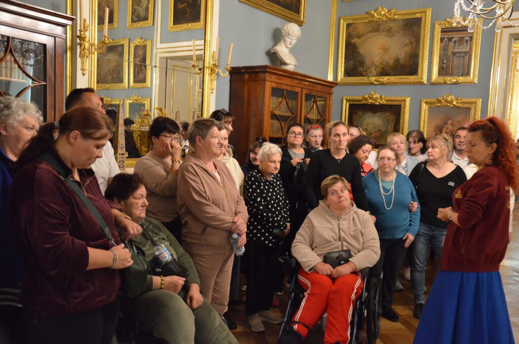 grupa zwiedzających stoi w zamkowej sali i słych przewodniczki