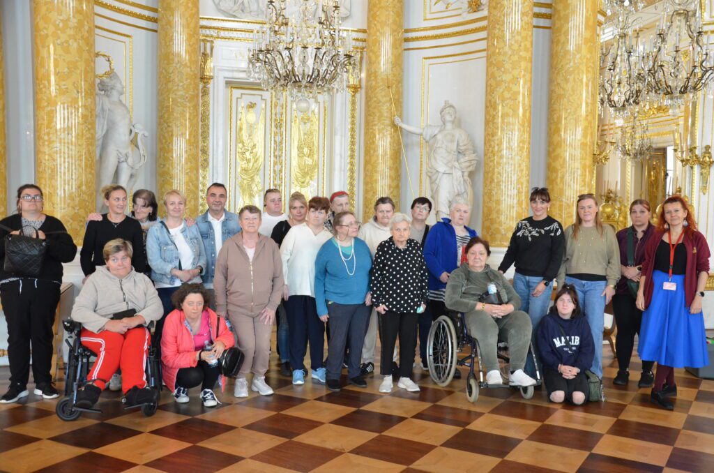 kilkoro ludzi stoi i pozuje do zdjęcia w sali bankietowej zamku królewskiego