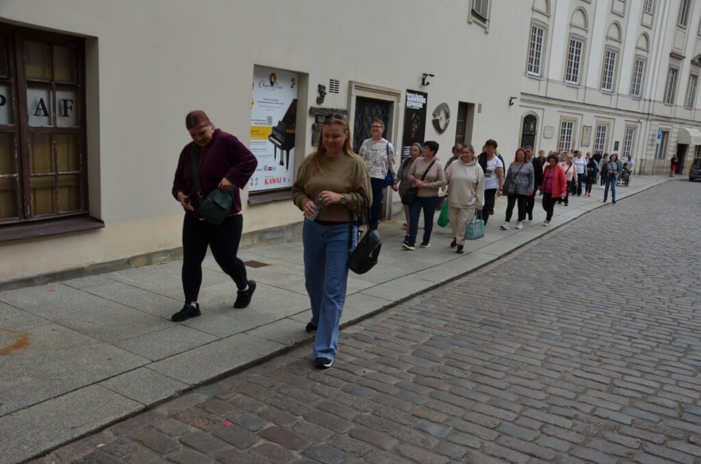 grupa wycieczkowiczów idzie uliczka we Warszawie do kolejnego miejsca