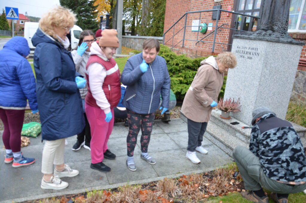 pomnik , prace przed, czesć pań stoi, niektóre sie schylają, sadzenie cebulek