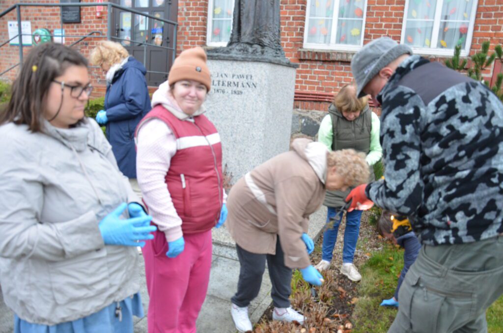 kolejne zdjęcie przed pomnikiem, panie w trakcie sadzenia cebulek