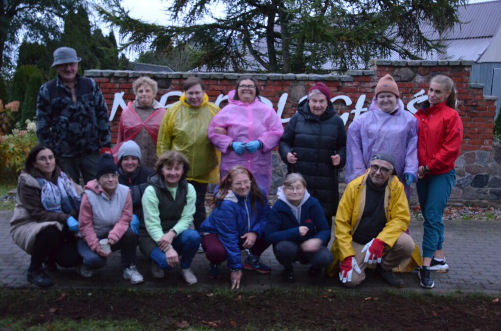 grupa ludzi stoi i pozuje do zdjęcia przed pomnikiem