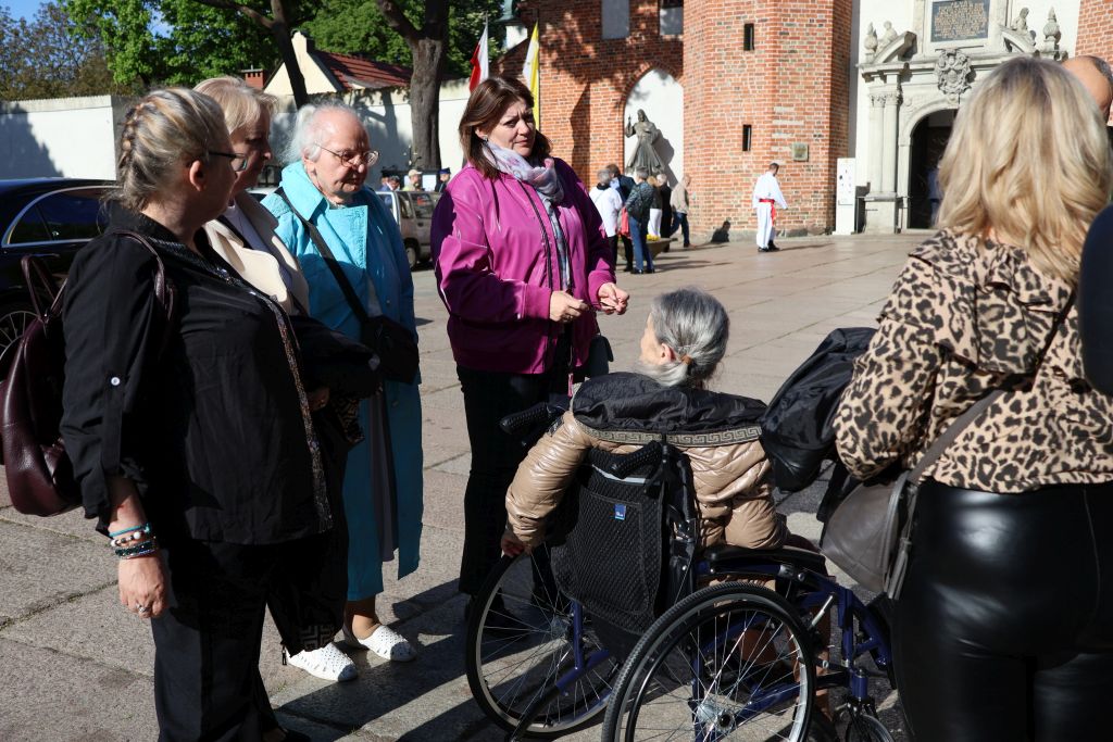 przed katedrą , panie stoją i sie zbierją, rozmawiaja, jedna siedzi na wózku