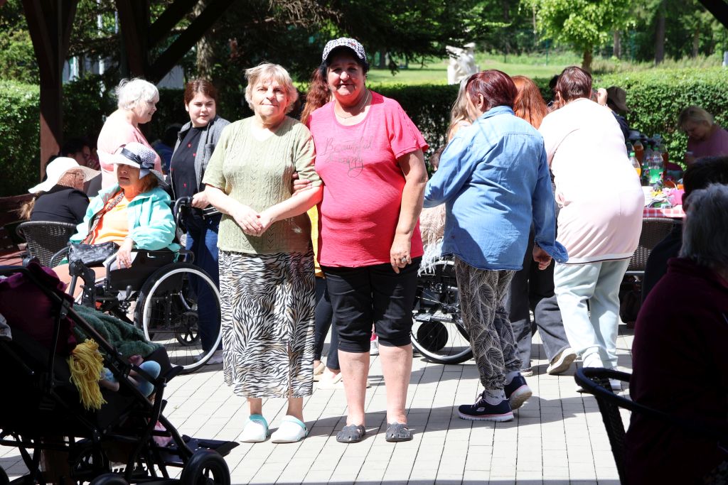 to samo miejsce 2 panie uśmiechięte stoją i pozują na tle innych bawiących się