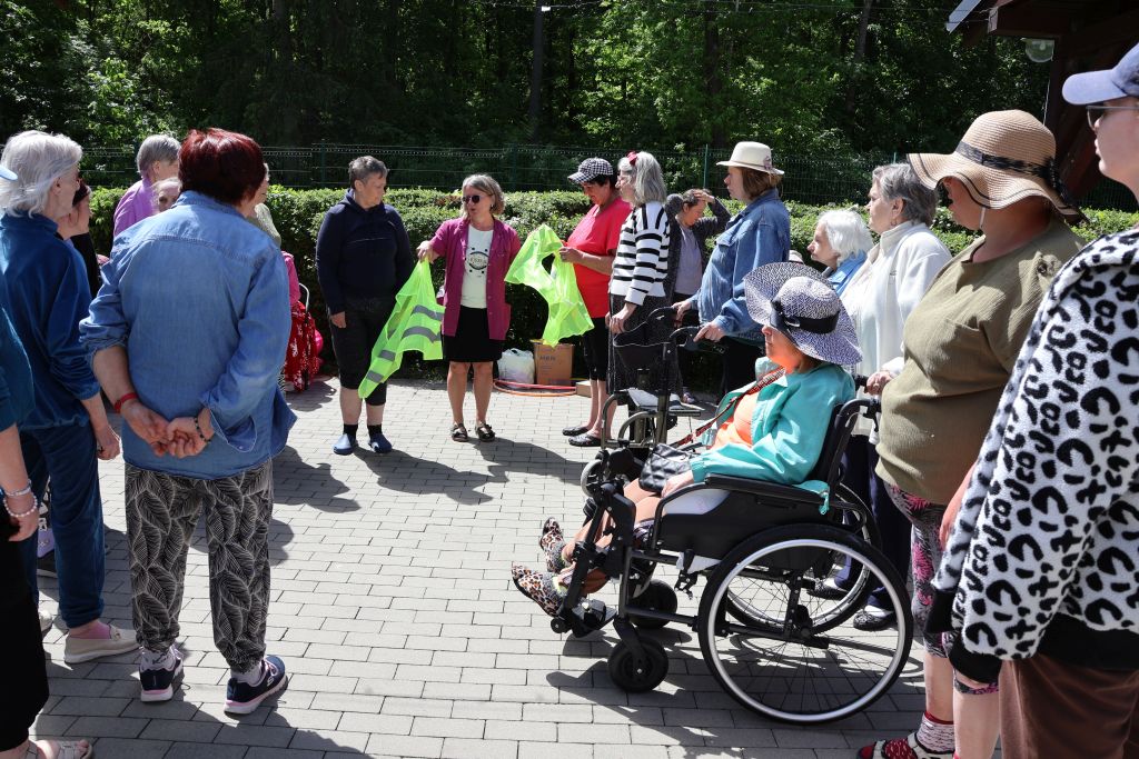 to samo miejsce w innej odsłonie panie stoja w półkole słuchają kobiety trzymającej zielone kamizelk i coś im tłumaczącej
