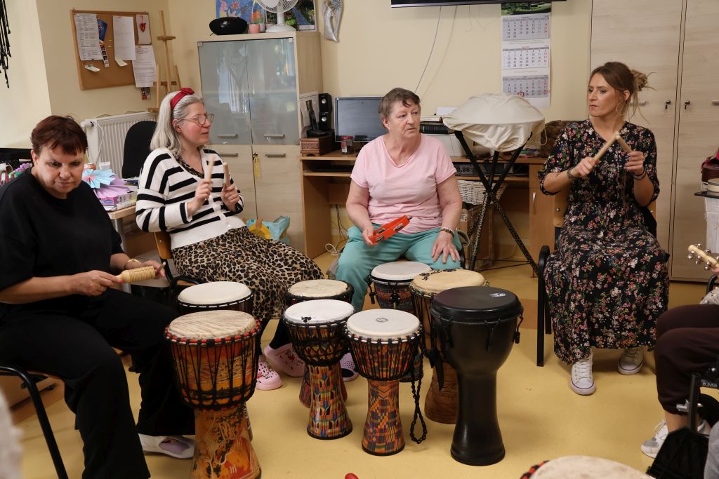sala ,zajecia muzyczne widac 8 bębnów, kobietę prowadzącą i 3 uczestniczki